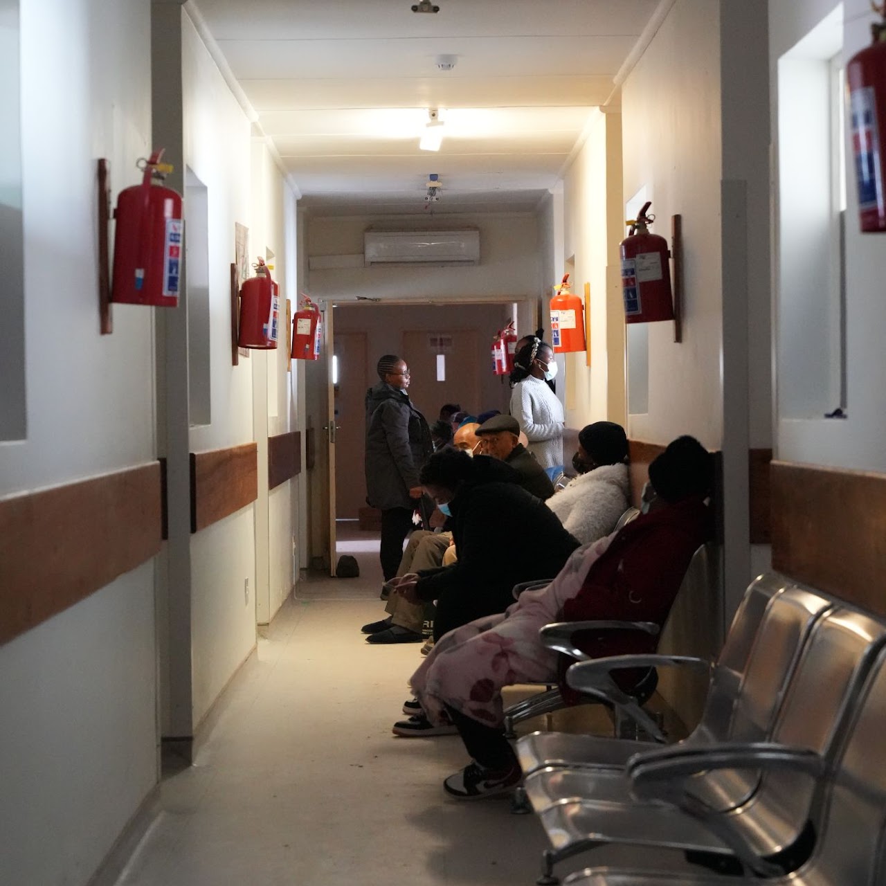 Our Impact, a healthcare facility, with several people seated on metal benches along the walls