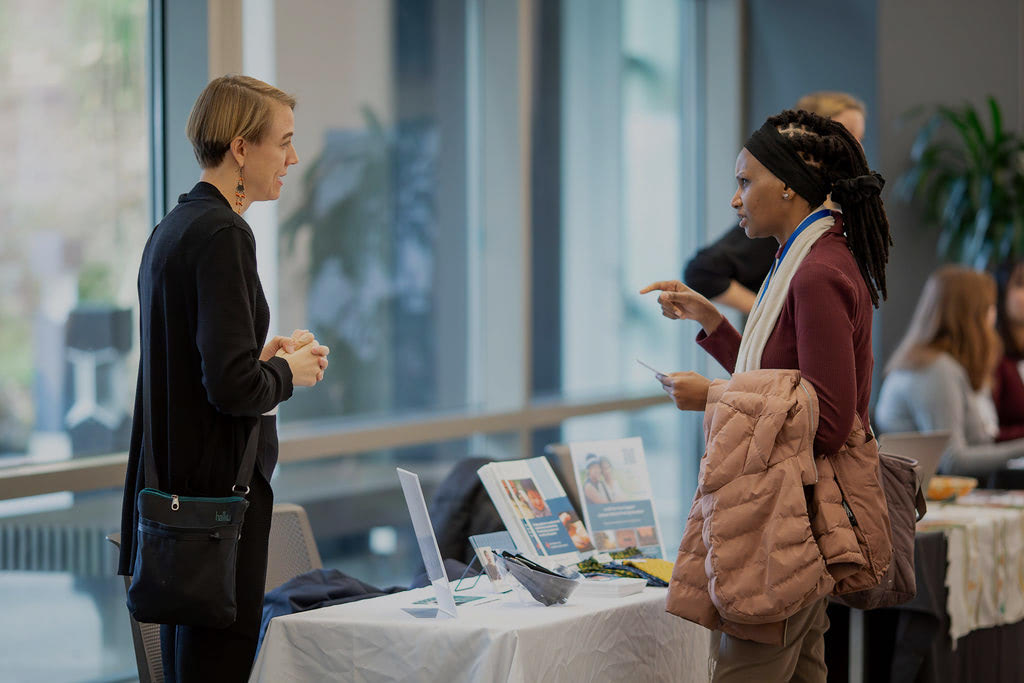 Become a Max Ambassador. A representative from The Max Foundation talks with a visitor at an event table.